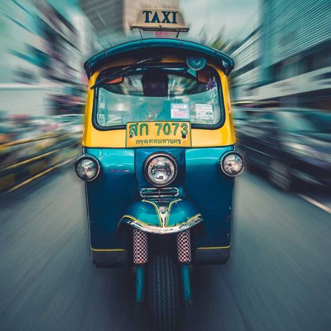 Ein blaues Taxi fährt schnell durch die Innenstadt in Thailand