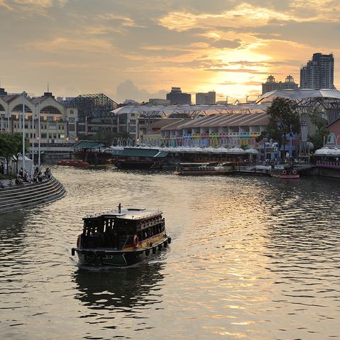 Ein Boot auf dem Singapur River bei Sonnenuntergang