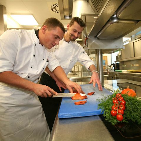 Koch Auszubildender lernt das Schneiden von Fisch