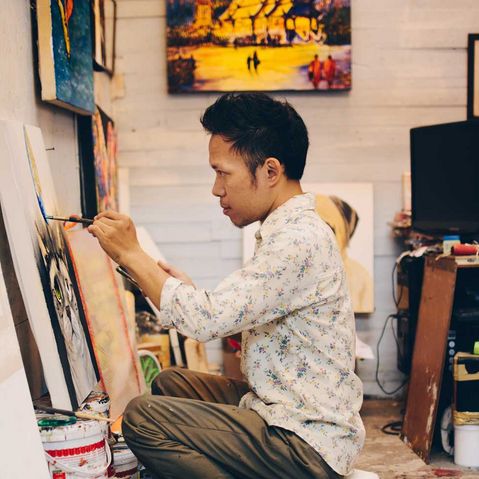 Ein thailändischer Junge malt in einer Galerie ein Bild mit einem Pinsel