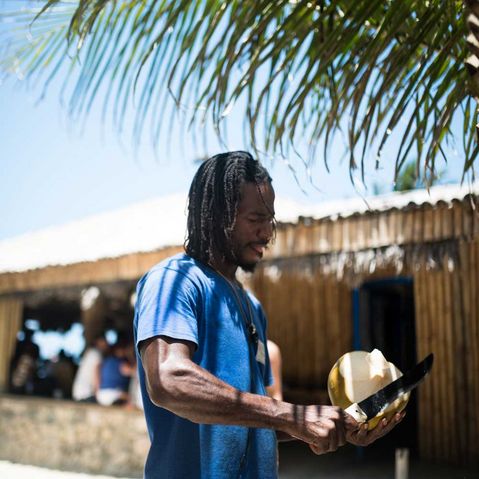 Ein Jamaikaner schält eine Kokosnuss