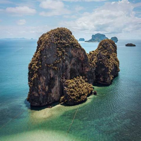 Ein Felsen ragt vor der Thailändischen Küste aus dem Wasser