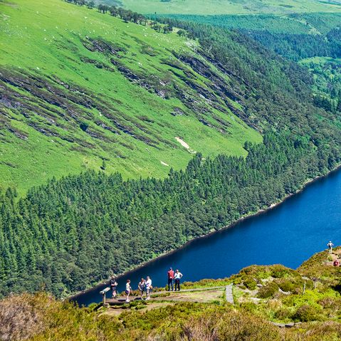 Mehrere Wanderer stehen auf einem Berg und genießen die Aussicht auf einen Fluss im Tal