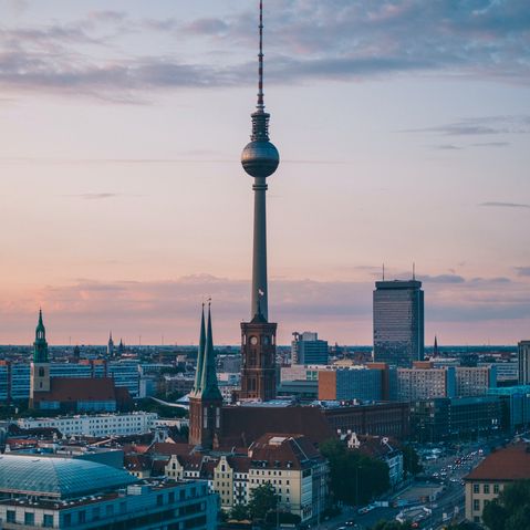 VisitBerlin Der Fernsehturm in Berlin am Alexanderplatz bei Sonnenaufgang mit lila Wolken
