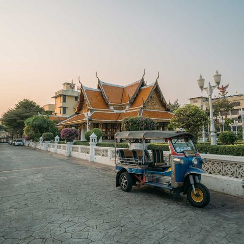 Ein Tucktuck steht vor einem Thailändischen Tempel auf der Straße