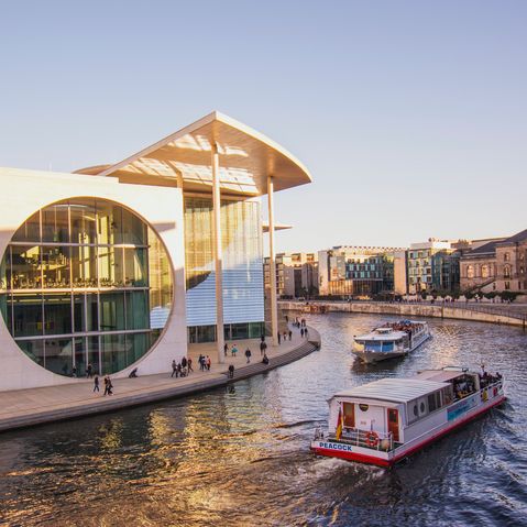 VisitBerlin Das Regierungsviertel in Berlin im Spreebogen bei Sonnenuntergang mit Touristenbooten