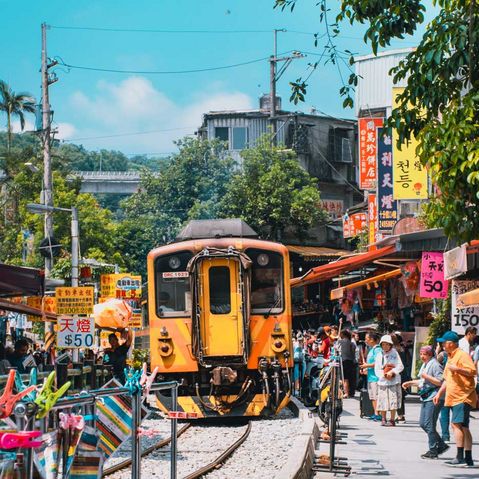 Ein gelber Zug der durch die Straßen in einem Dorf in Taiwan fährt