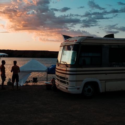 Wohnmobilreisen mit TUI Deutschland Wohnmobil am Strand mit jungen Menschen, welche unter einem Zelt daneben sitzen von TUI Camper